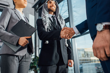 cheerful arabic businessman shaking hands with partner on meeting with translator in office