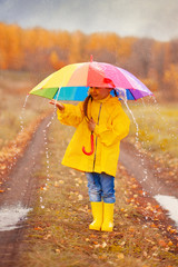 Happy kid catches raindrops in autumn park.