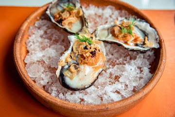 Fresh oysters in shell topping with fried shallot, chili paste, dill and Thai style seafood sauce served on ice