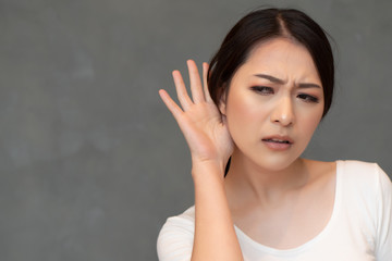 woman listening to something; portrait of asian woman with hearing ear, concept of rumor, gossip, hearing loss, whispering, hard of hearing, fake news, good news, bad news