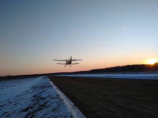 old biplane plane on takeoff after taking off from the runway rear view of a winter landscape at...