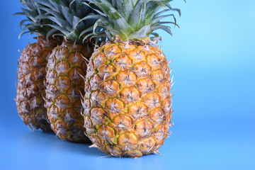 Three close up pineapples on blue background