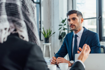 arabic businessman talking with caucasian partner in office