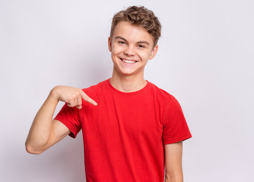 Portrait of handsome teen boy pointing oneself, on grey background. Emotions and signs concept. Happy smiling child looking at camera. Young student points fingers at himself