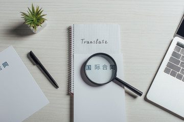 top view of hieroglyphics, magnifier and laptop on translator workplace
