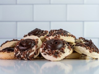 Chocolate covered thumbprint cookies with sprinkles on a white glossy surface with the reflection showing and a white subway tile background.  Delicious sweetness!