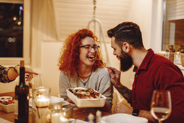 Young man feeding his girlfriend while having dinner at dining table.