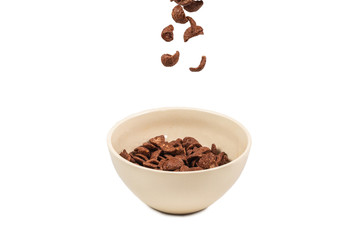 Chocolate corn flakes falling to the white bowl isolated on white. Motion.