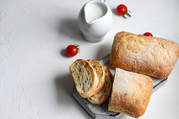 Ciabatta with rosemary, olive oil and cherry tomatoes on a wooden board. On white background.