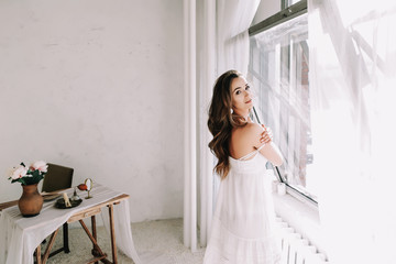 Portrait of a young beautiful woman. Bride in elegant classic wedding dress. Morning of the bride. Wedding preparations.