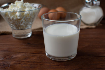 Homemade rustic crumbly cottage cheese with milk on a wooden background. Still-life.