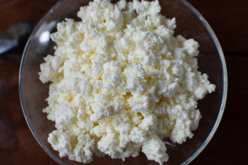 Homemade rustic crumbly cottage cheese with milk on a wooden background. Still-life.