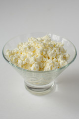 Homemade rustic crumbly cottage cheese on a white background.