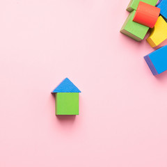 Children's wooden toys on a pink background concept zero west. Small houses the designer from developing color cubes