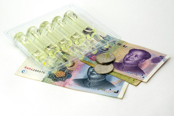 concept vaccination and treatment of coronovirus in china ampoules with medicine and chinese money yuan on the white background
