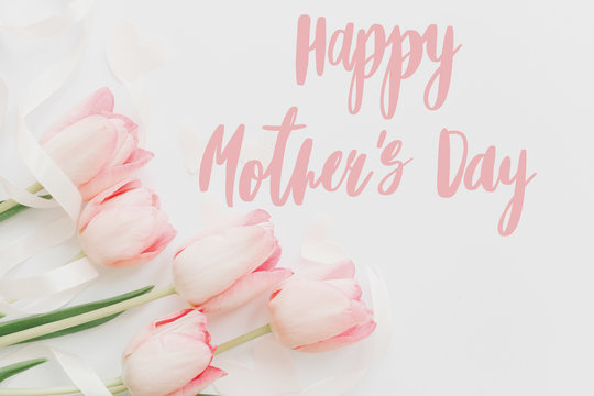 Happy mother's day.  Happy mothers day text and pink tulips floral border on white background. Stylish soft image. Floral Greeting card. Happy Mothers day. Handwritten lettering