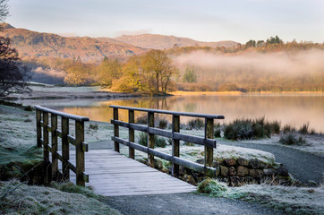 Early morning frost on a foot bridge with mist over Grasmere in the Lake District Cumbria 