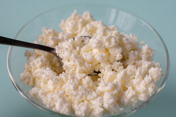 Homemade rustic crumbly cottage cheese on a blue background.