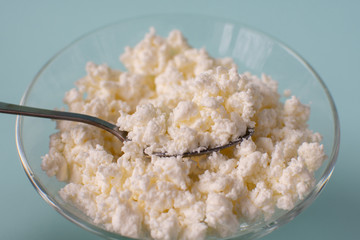 Homemade rustic crumbly cottage cheese on a blue background.