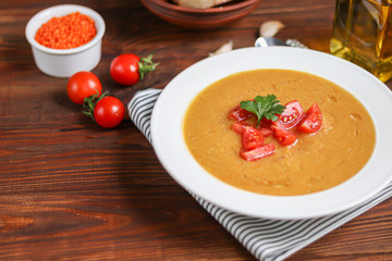 Vegetable soup with lentils on a wooden background. Served with chopped cherry tomatoes. Nearby are pieces of ciabatta. Raw groats in the background. Vegetarian dish.