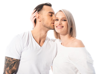 happy young tattooed couple hugging and kissing isolated on white