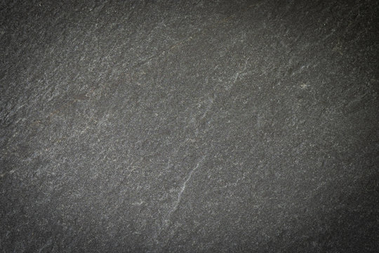 Black stone slate background. Natural hard rock dark grey texture. Abstract surface rough pattern with darkness and vignet. Blank copy space for design backdrop.