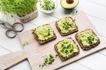 Microgreen in pot, scissors and sandwiches on wood board