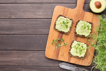 Sandwiches with avocado and microgreen on kitchen board