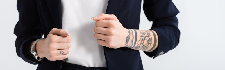 cropped view of successful young tattooed businesswoman with hands on blazer isolated on white,...