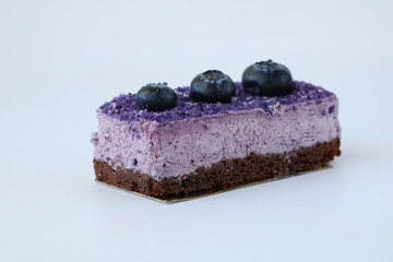 Tasty purple blueberry mousse cake with blueberry on white background, horizontal, side view, copy space