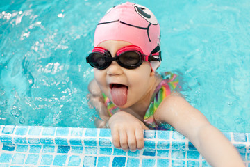 baby girl enjoying swimming in a pool, swimming lesson of young children in the pool, learning to...