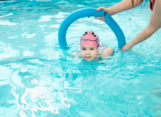 baby girl enjoying swimming in a pool, swimming lesson of young children in the pool, learning to swim in the childrens pool, early childhood development