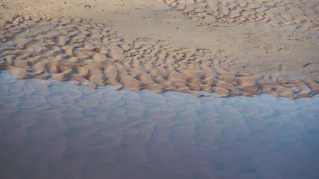 Static sandy bank of the river with traces of tourist shoes and a variable even flow of water in the Baltic Dune River. Latvia