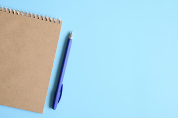 notebook or sketchbook made of craft paper and a pen on a blue background. space for text