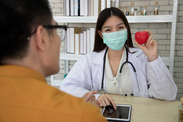 a nutritionist doctor is educating a young businessman about taking heart disease and supplements via tablet in the consultation room. Concept about health care and good health.