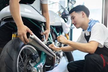 Fototapeta na wymiar Asian mechanic man fixing the retro motorcycle in the garage. Film effected - Selective focused