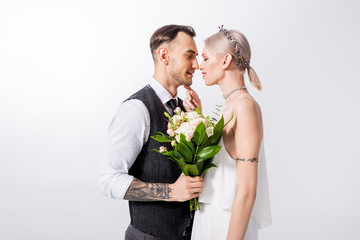 beautiful tattooed bride and handsome bridegroom standing nose to nose isolated on white
