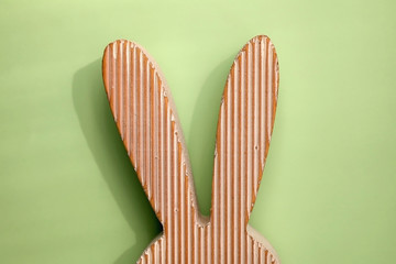 Wooden Easter bunny decoration in front of pastel green background. 