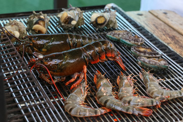 Lobster, rock lobster and mix seafood barbecue cokking on grill - seafood dinner party concept.