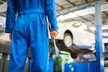Mechanics holding wrench in the workshop garage. Auto car services concepts