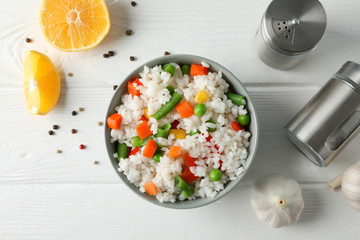 Composition with bowl of delicious rice on wooden table, top view
