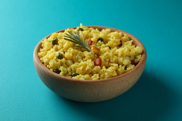 Wooden bowl with delicious rice on turquoise background, close up