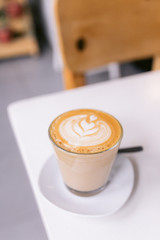 One cappuccino on a white table in a coffee shop