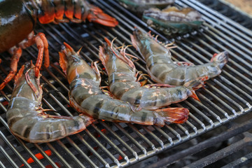 Lobster, rock lobster and mix seafood barbecue cokking on grill - seafood dinner party concept.