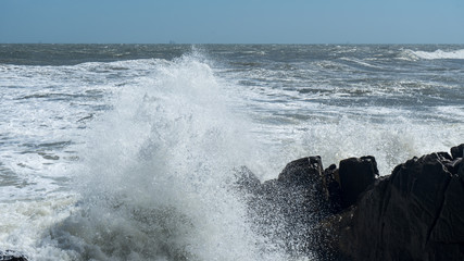 Ocean waves crashes on the rocks, windy weather on ocean.