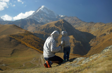 Little boy with father looking at incredible snowy mount glacier and brown hills at autumn time. Travelling with kids