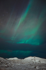 Fototapeta na wymiar A beautiful northern lights also called Aurora Borealis over the Iceland. Winter time in Scandinavia is very magical and brings a lot of tourists from all over the world to see it