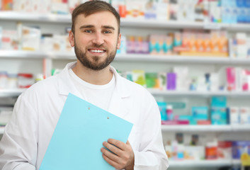 Professional pharmacist with clipboard in modern drugstore