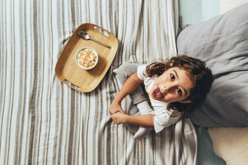 top view of a teasing little girl with a breakfast