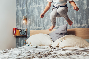 detail of a little girl legs jumping high at bed
